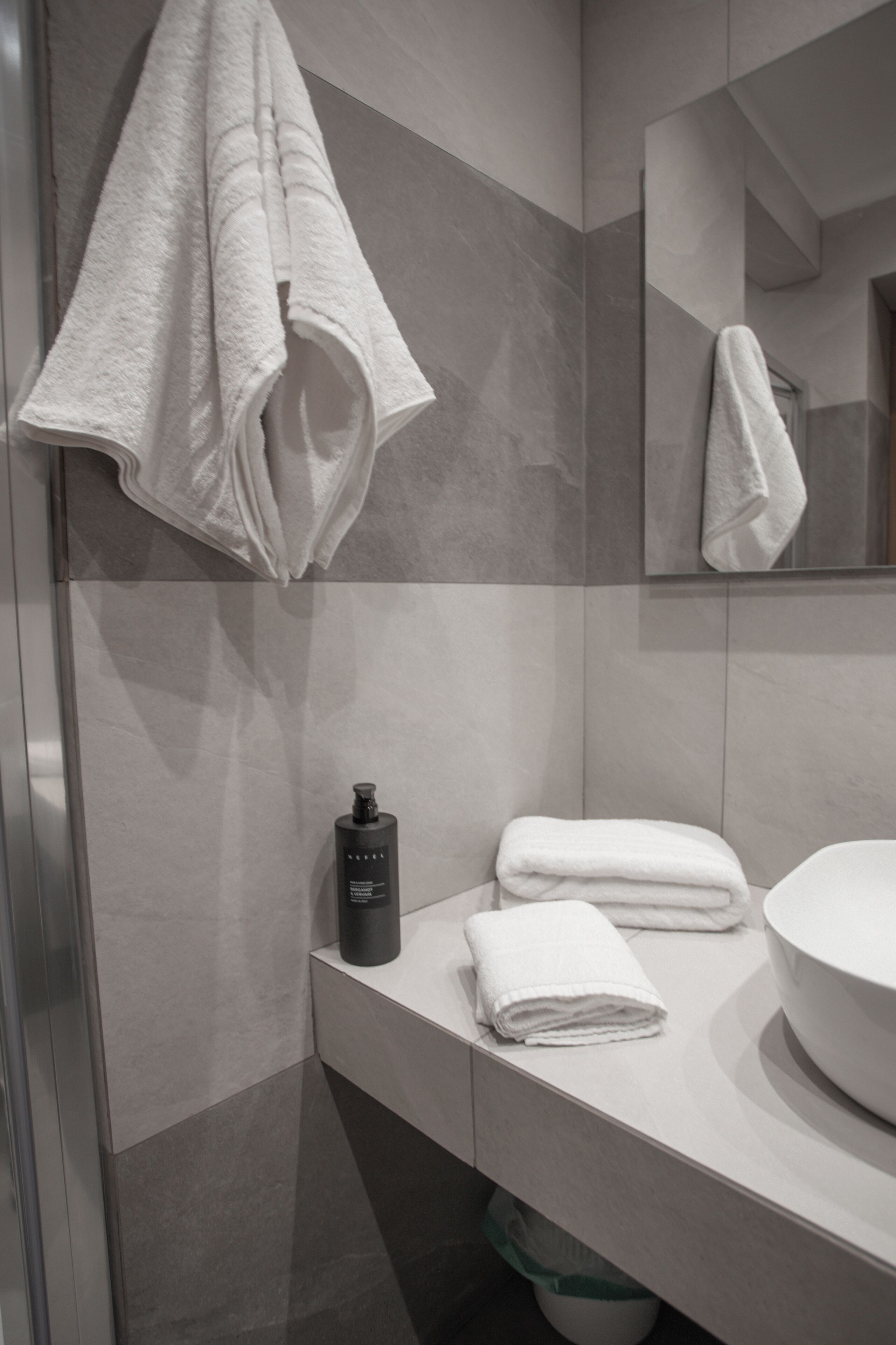 Une salle de bain moderne avec un grand miroir, un lavabo et deux serviettes.