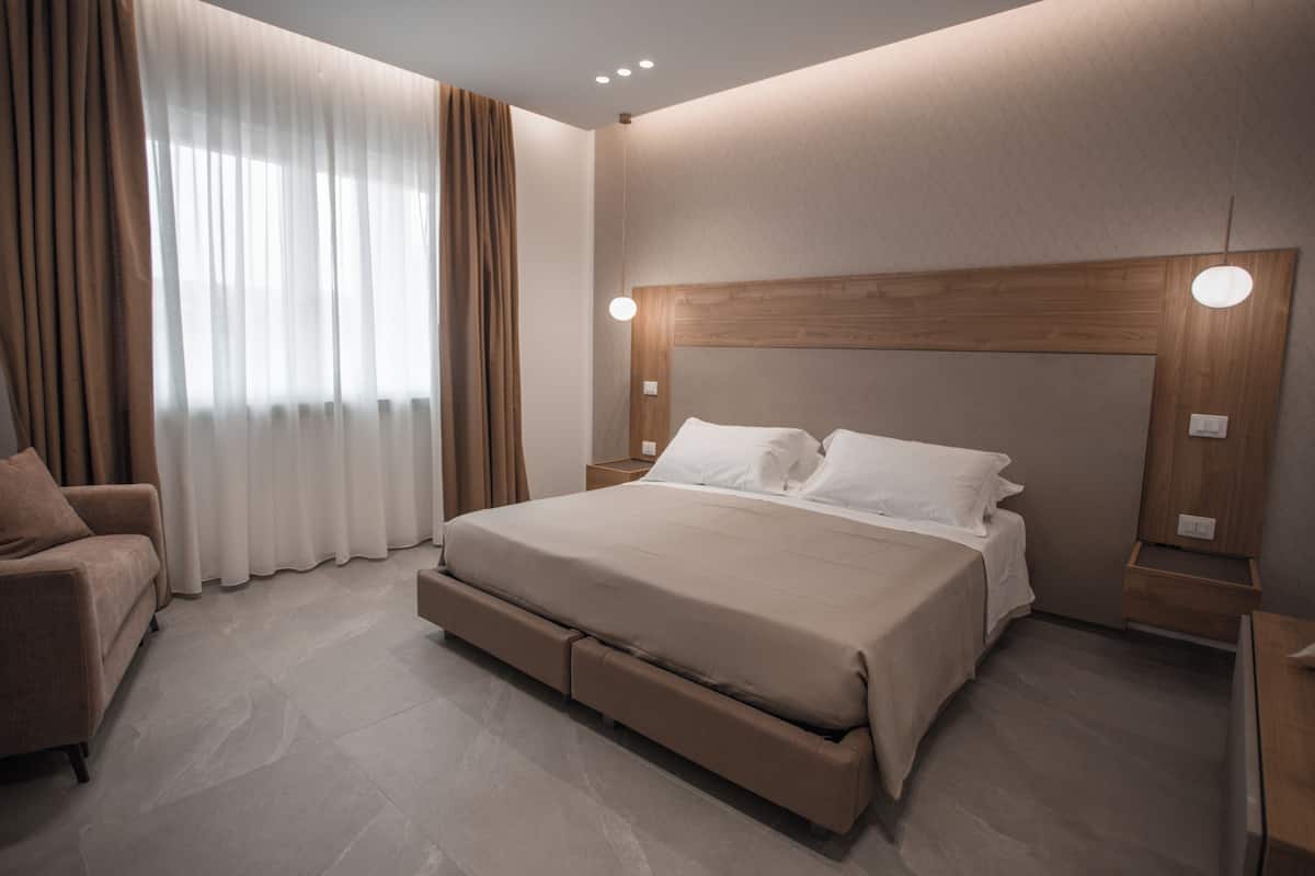 Ein modernes Schlafzimmer mit einem großen Bett, einer Couch und einem hölzernen Kopfteil.