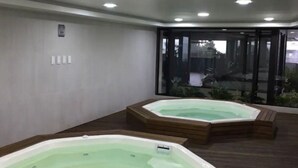 Deux bains à remous dans un espace intérieur moderne, avec un plancher en bois et des murs en verre.