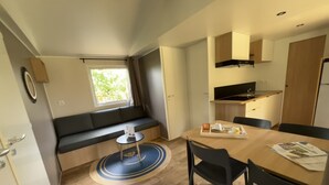 A compact kitchen with a dining area, a small round table, and a built-in bench with cushions. - Camping du Lion d'Angers (Le Lion-d'Angers)