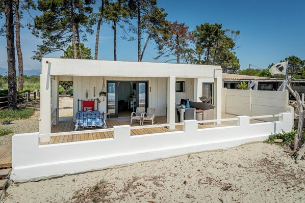 Una propiedad frente a la playa con fachada blanca, un espacio de estar techado al aire libre y vista al océano.