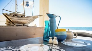 Et bord dækket med tallerkener, en kande og saltshakers med udsigt til havet.