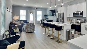 A modern kitchen with white cabinetry, stainless steel appliances, and pendant lighting. - Ocean Pearl Villa by Resort Collection (Panama City Beach)