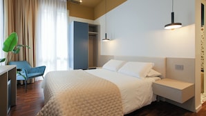 Una habitación de hotel moderna con una cama grande, mesitas de noche, un escritorio y una silla.