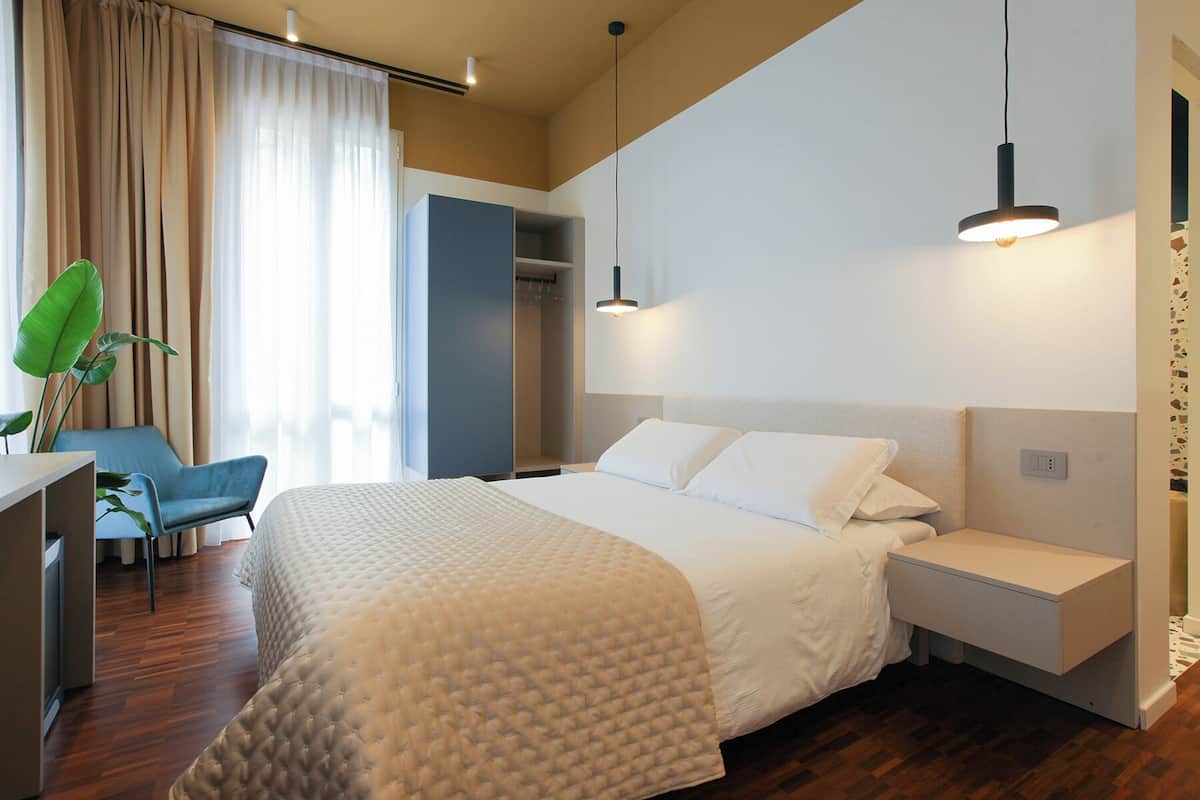 Une chambre d’hôtel moderne avec un grand lit, des tables de chevet, un bureau et une chaise.