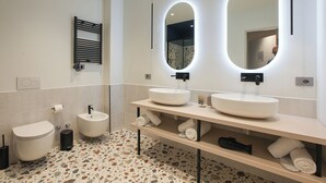 Un baño moderno con dos lavamanos, un inodoro y un perchero para toallas.