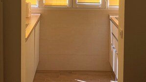 Un couloir étroit, avec une fenêtre au fond, une porte à gauche et un comptoir à droite.