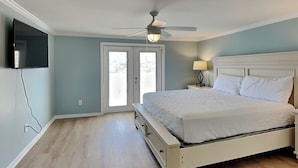 Ein Schlafzimmer mit einem Bett, Deckenventilator und einem an der Wand befestigten Fernseher.