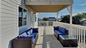 Eine überdachte Terrasse mit zwei Sofas und einem Tisch, mit Blick auf eine Wohngegend.