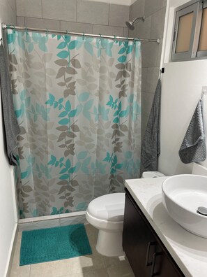 Een douche, handdoeken, zeep, toiletpapier