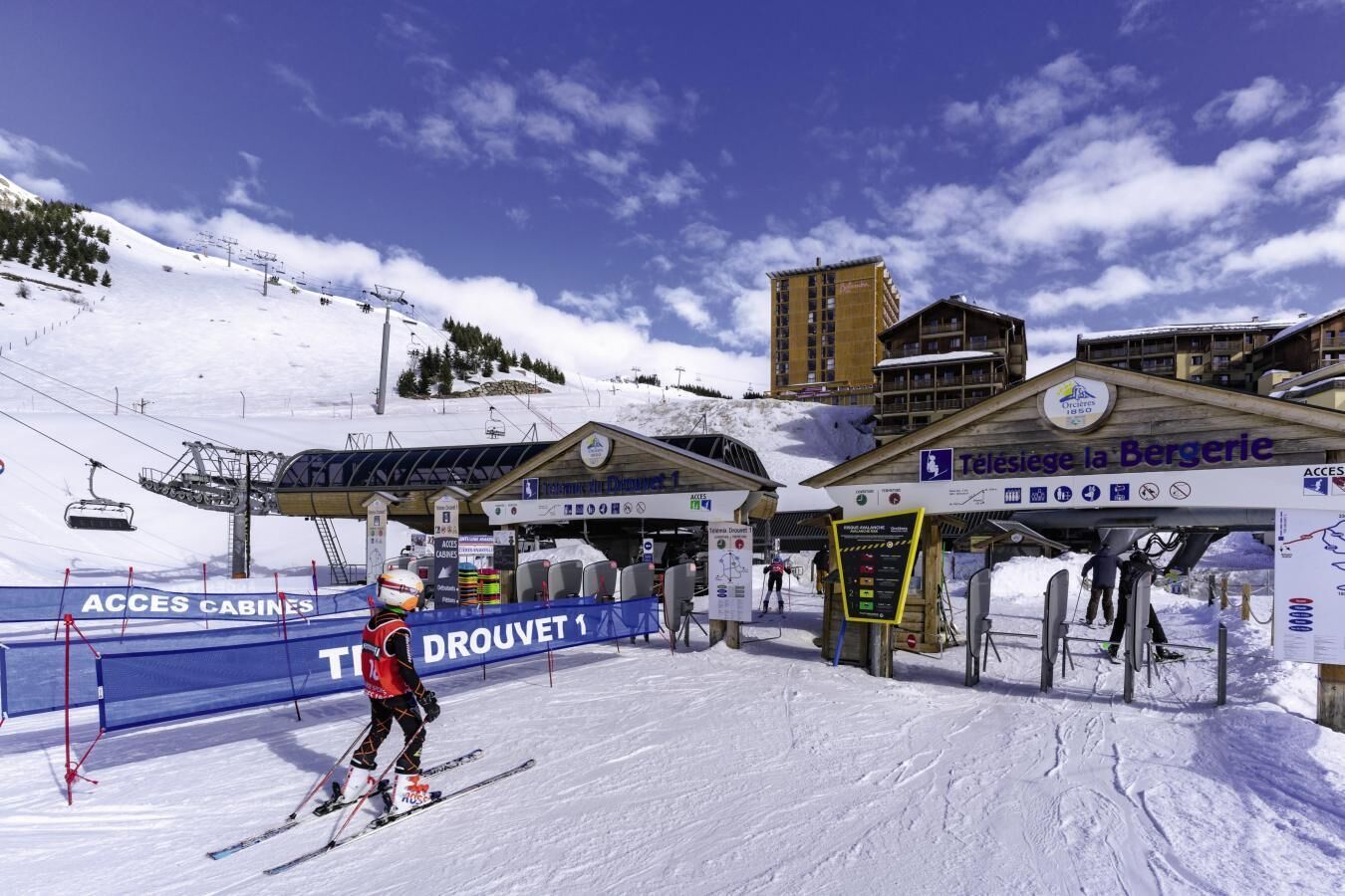 A ski resort with a ski lift, a sign for 'Téléseil la Bergerie', and a 'DROUET 1' sign.