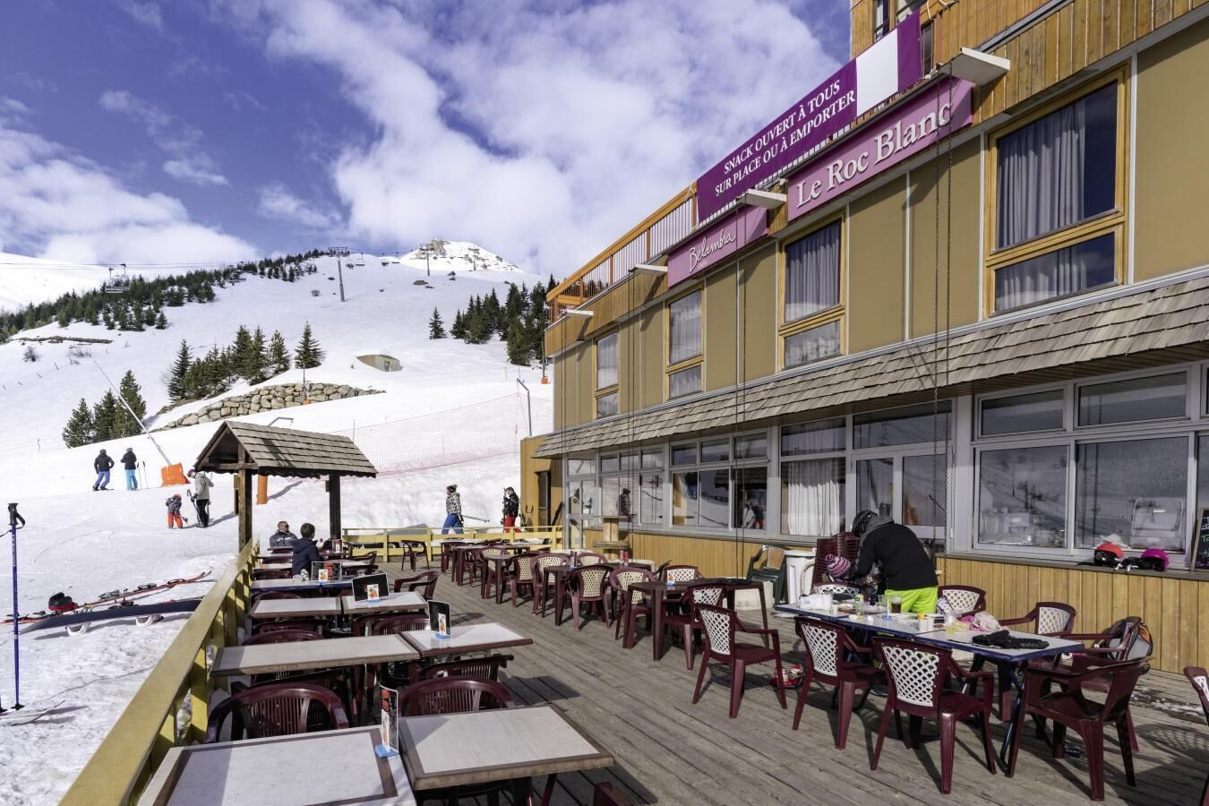 Un restaurant avec une terrasse offrant une vue sur une montagne enneigée.