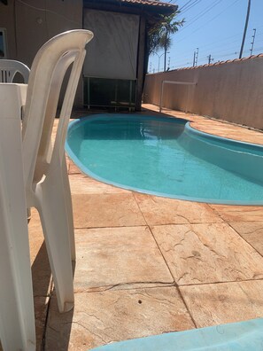 Una piscina de borde curvo, rodeada de baldosas de piedra.
