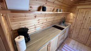 Una cocina compacta con paredes de madera, un lavamanos empotrado y una máquina de café.