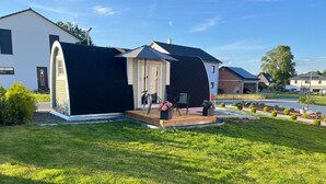 Una casa moderna con un espacio exterior cubierto, un pequeño patio y un césped bien cuidado.