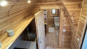 Una cabaña de madera compacta con kitchenette, un baño pequeño y una zona de descanso.