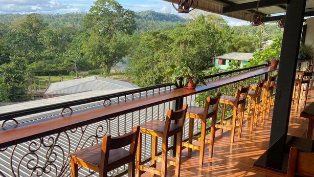 An outdoor seating area with a view of a lush landscape. - Hostal la Colina (Tena)