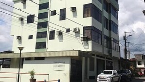 A multi-story building with a flat facade, several windows, and air conditioning units. - Hostal la Colina (Tena)