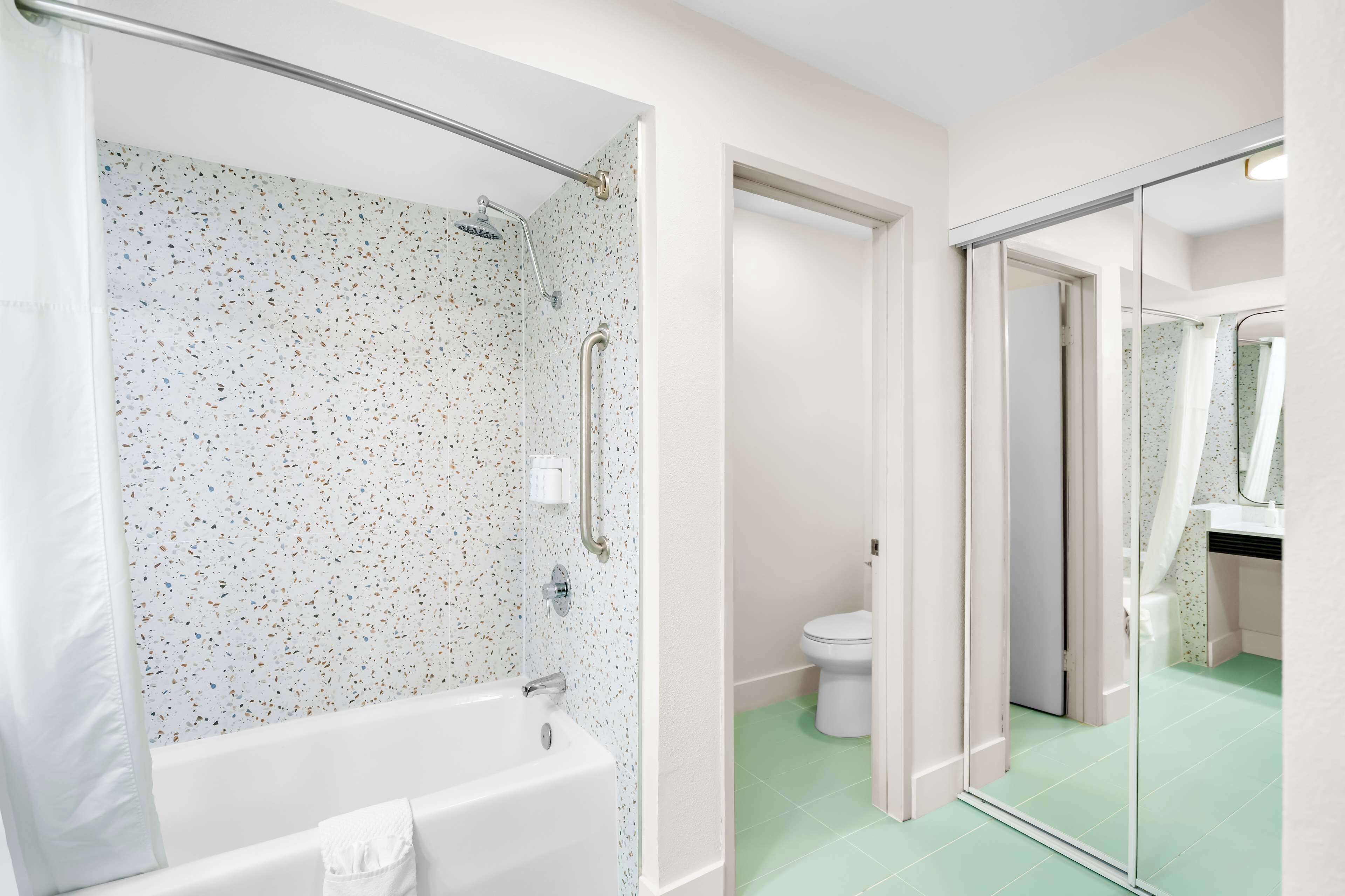 A bathroom with a shower, toilet, and a bathtub.