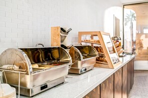 A buffet setup with various food stations, including a meat station and a pastry display.