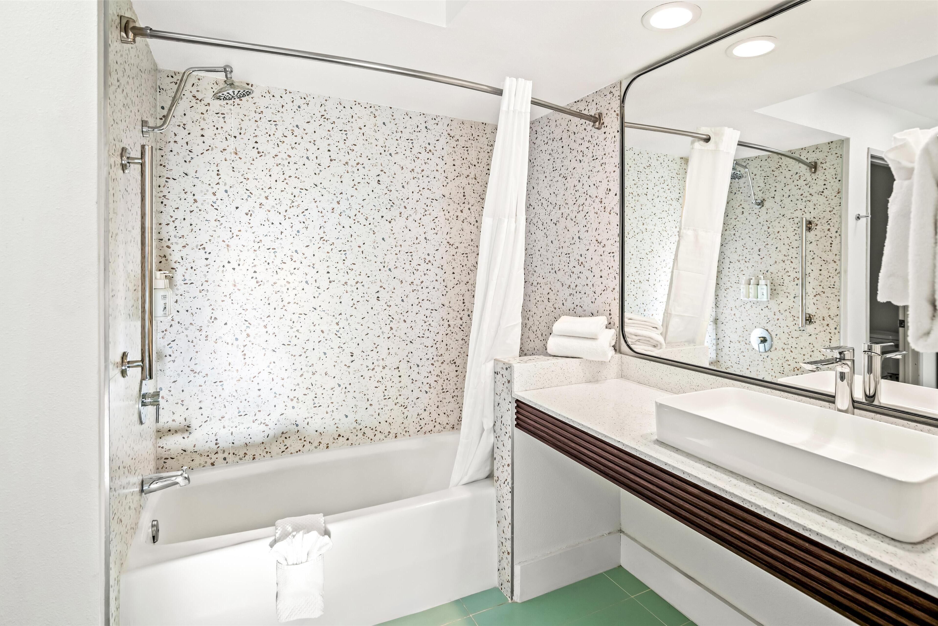 Een moderne badkamer met een vrijstaand bad, een grote spiegel en een witte wastafel.