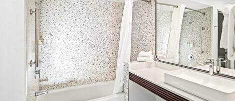 A modern bathroom with a freestanding bathtub, a large mirror, and a white sink.