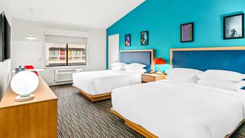 A hotel room with two beds, a TV, a window with a view of a balcony, and artwork on the walls.