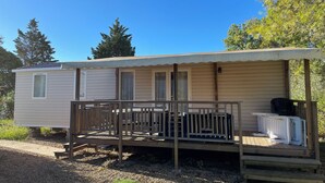 Une maison mobile dotée d’un porche couvert, d’une petite terrasse et d’une fenêtre.
