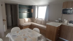 Un espace de vie compact comprenant un coin repas, une kitchenette et un coin salon avec un canapé et des fauteuils.