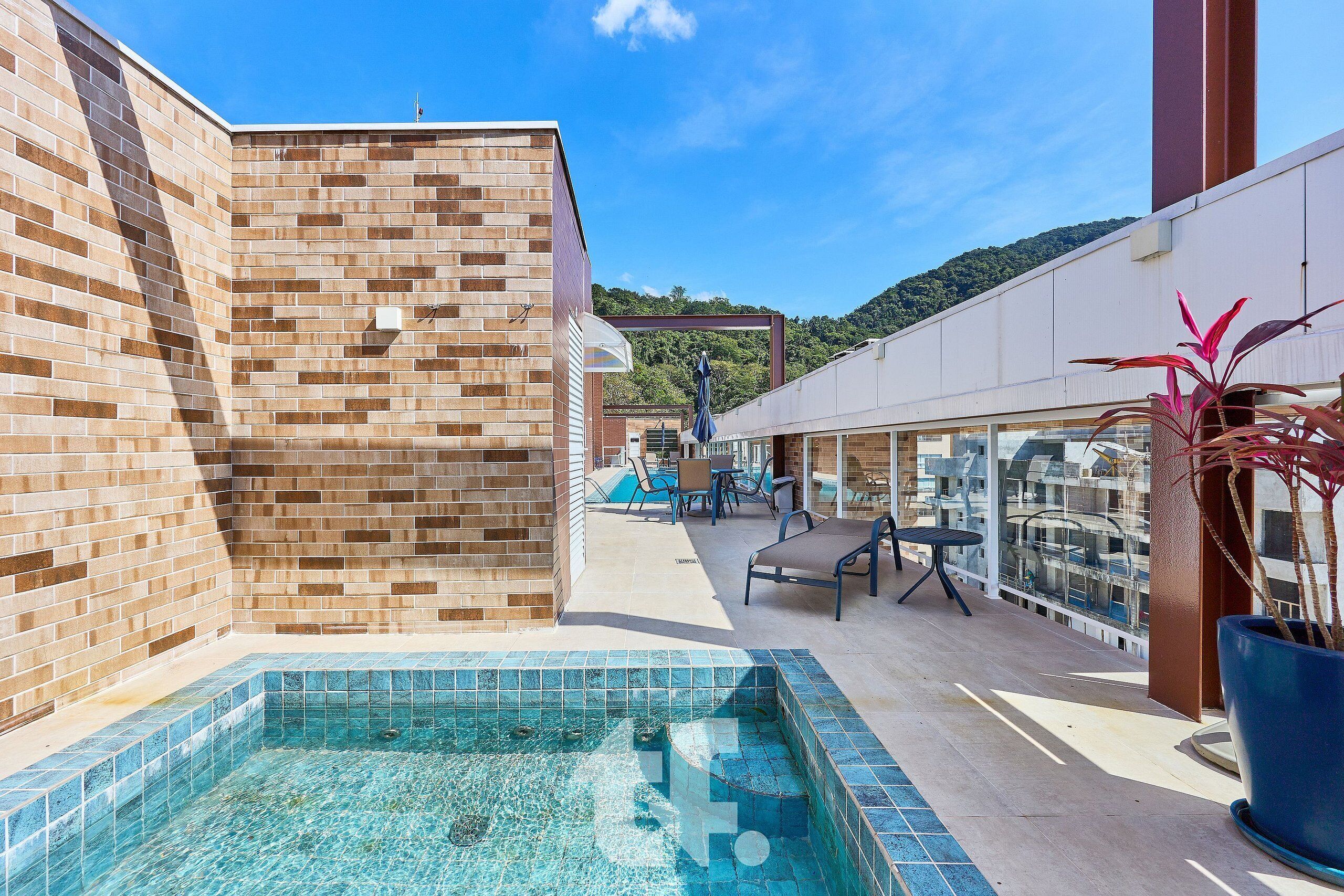 A swimming pool with tiled edges, a brick wall, and a seating area with chairs and a table.