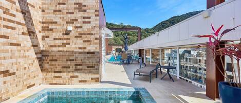 A swimming pool with tiled edges, a brick wall, and a seating area with chairs and a table.