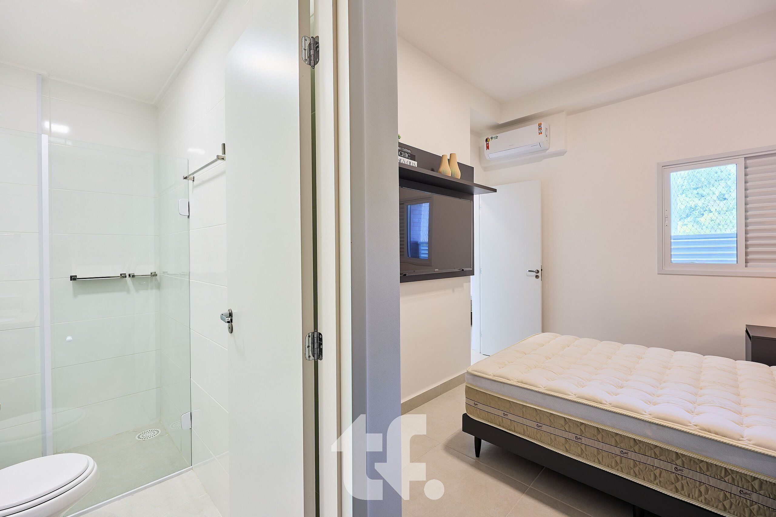Un baño moderno con cabina de ducha de vidrio, un inodoro y una cama con colchón y almohadas.