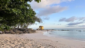 A sandy beach with footprints, a yellow lifeguard tower, and a calm sea. - 4-bedroom villa in wonderful Oistins with pool (Oistins)