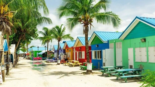 A row of colorful beach huts with picnic tables and palm trees. - 4-bedroom villa in wonderful Oistins with pool (Oistins)