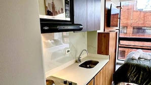 A modern kitchen with a built-in stove, sink, and wooden cabinets. - 605-Estudio luminoso con balcón  (Bogotá)