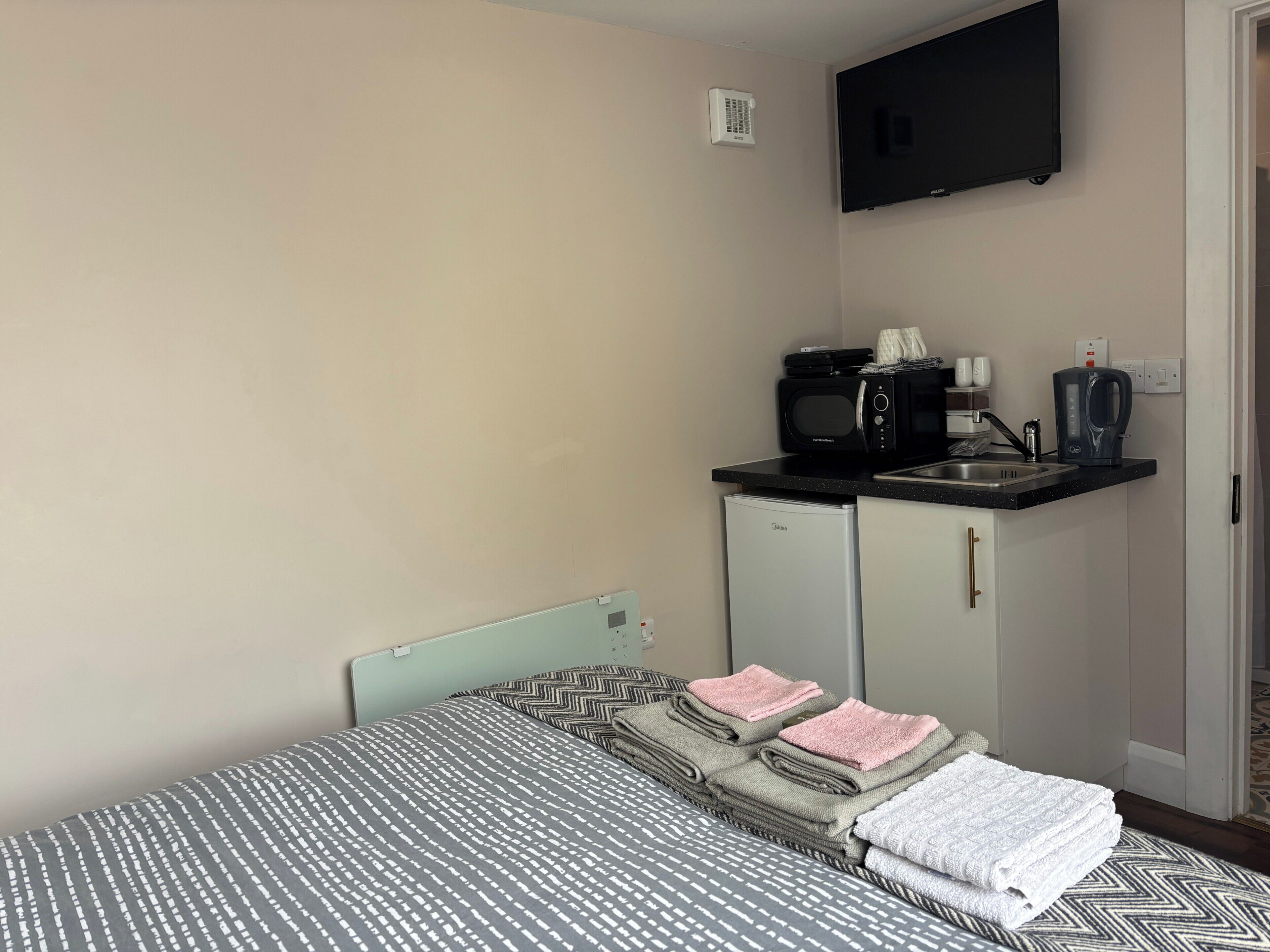 Une chambre compacte comprenant un lit, une kitchenette équipée d’un four à micro-ondes, d’une machine à café et d’un petit réfrigérateur.
