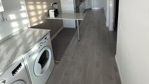 Moderni keittiö, jossa on integroidut kodinkoneet, keskeinen keittiösaareke ja pyykinpesutila.