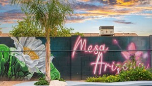 A wall with a mural of a flower and the words 'Mesa Arizona' in neon. - Heated Pool + Hot Tub | Backyard Resort | Games (Mesa)