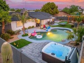 A backyard with a swimming pool, hot tub, and outdoor seating area.