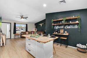 A modern kitchen with a wooden island, a bar area with shelves, and a neon sign.