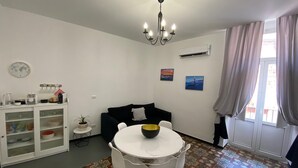 A compact living space with a dining area, a black sofa, a white table with chairs, a chandelier, and a patterned floor. - Apartment in the Borgo Antico, within walking distance of Largo Albicocca (Bari)