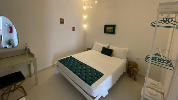 A bedroom with a bed, bedside table, mirror, and a clothing rack. - Apartment in the Borgo Antico, within walking distance of Largo Albicocca (Bari)