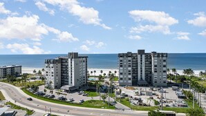A modern hotel complex with multiple high-rise buildings, a parking area, and a view of the beach and ocean. - Beachfront Bliss: 2-Bed/2-Bath Condo with Stunning Views! (Fort Myers Beach)