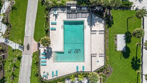 An aerial view of a hotel with a large swimming pool, multiple lounge areas, and a well-maintained garden. - Beachfront Bliss: 2-Bed/2-Bath Condo with Stunning Views! (Fort Myers Beach)