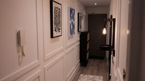 A hallway with framed artwork on the walls, a telephone, and a light fixture. - Stylish, Luxury Apartment Sleeps 4 - Southampton (Southampton)