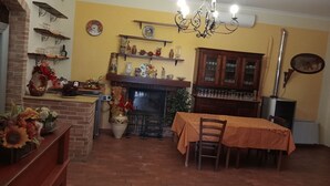 Un comedor con chimenea de ladrillo, una araña y una mesa lista para cuatro comensales.