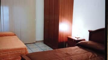 A bedroom with two beds, a wardrobe, and an air conditioning unit.