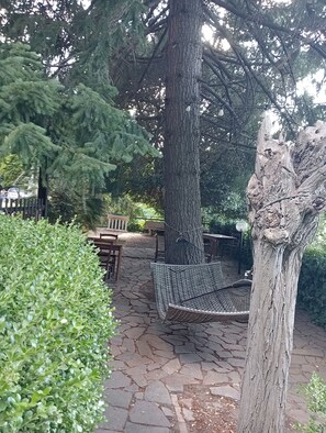 Eine terrasse aus Steinplatten mit einer Hängematte, einem Holztisch und Stühlen.