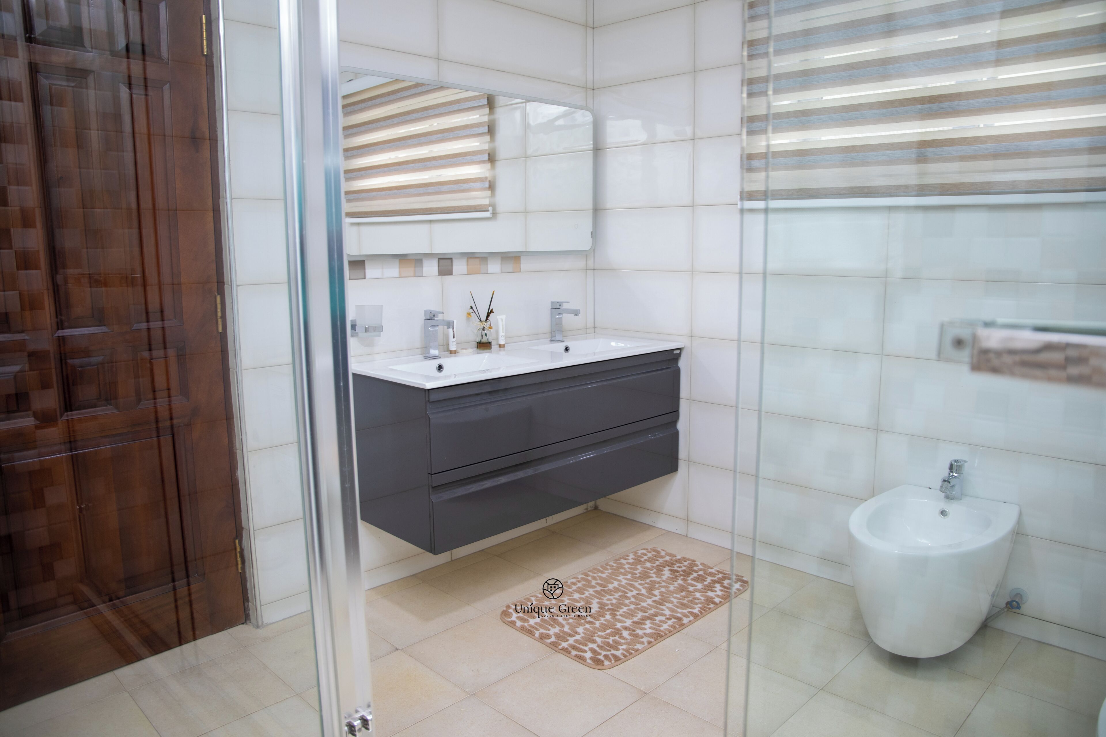 Un baño moderno con cabina de ducha de vidrio, un lavabo blanco con gabinete oscuro y un bidé.