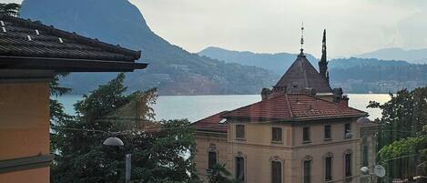 A building with a red-tiled roof, a roundabout with cars, and a mountain in the background.